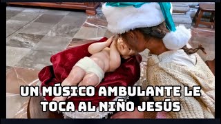 Un músico ambulante con su familia le toca al Niño Dios en la víspera de Navidad