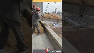 Two workers unload sand delivered from a crane on a high floor of a house