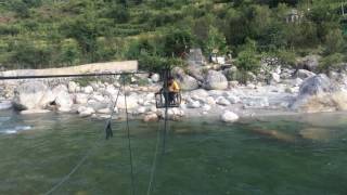 Crossing river using trolley bridge built on a ropeway in Tirthan Valley, Banjar, Kullu