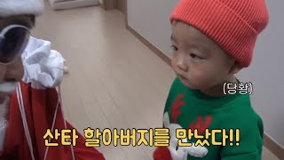 A 18-month-old baby meeting Santa Claus for the first time in his life.