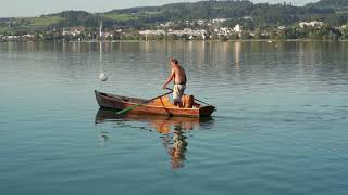 A fisherman in a boat with oars in the middle of the lake ( Video Background Stock Footage Free )