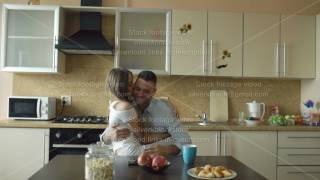 Attractive young couple embracing and kissing early morning in the kitchen while man have breakfast