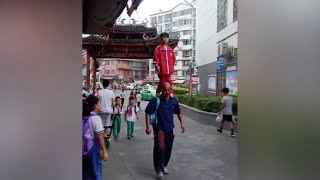 Chinese girl stands on grandfather's shoulders on her way to school