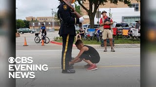 11-year-old boy ties officer's shoelaces during Fourth of July parade