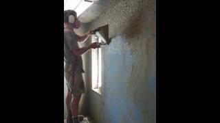 Using a sprayer to apply earthen plaster brown coat over Durisol blocks.