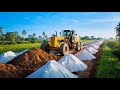 A large motor grader in action, pushing and leveling a dirt surface on a road construction site