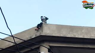 Who is this person, and why have they climbed onto the bus stand roof??