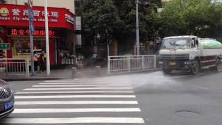 まわりに目もくれず必死に道路掃除をする散水車@China