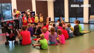 Kids help stop Henri the evil cat from gluing the library doors shut, at "The Heroes in You" program
