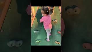 Toddler Climbing at Playground (儿童在室外游乐场攀岩）。