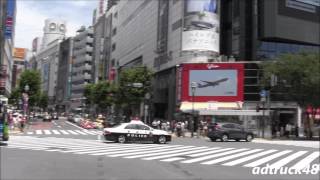 渋谷駅前スクランブル交差点を渡る歩行者の間を緊急走行するパトカー