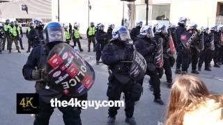 4K UHD - Crowd of masked protesters standing in line near a riot police line