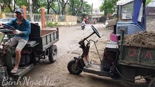 Three-wheeled tractor carrying construction materials