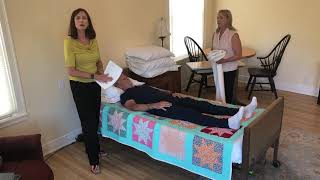Demonstration on 1 person placing a turn or draw sheet under a patient.