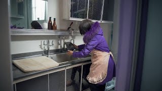 The eldest daughter is playing coquetry in her mother's arms  and her mother cooks chicken soup for