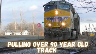 A grain train pulls slowly over 90 year old track with over 80 cars