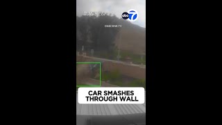 Car smashes through brick wall