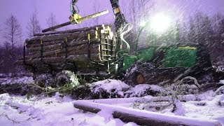 John Deere 1110E logging in snowy winter forest, skiled operator