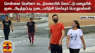 சென்னை மெரினா கடற்கரையில் கொட்டு மழையில் குடைபிடித்தப்படி நடைபயிற்சி செய்யும் பொதுமக்கள்