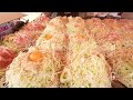 a long line at the morning market stalls okonomiyaki made with 24 heaped cabbage slices in a row.