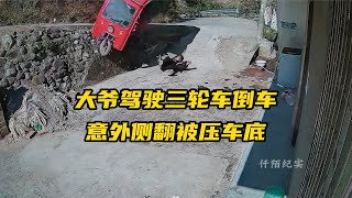 大爷驾驶三轮车倒车，不慎侧翻被压车底，邻居及时救援