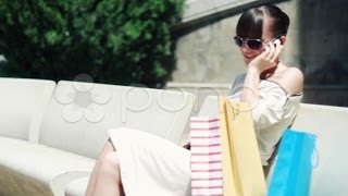 Attractive woman with shopping bags talking on the phone NTSC. Stock Footage