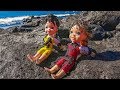 Elsa and Anna toddlers play with black sand on the beach