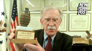 John Bolton shows Piers Morgan a trophy in the form of a hand grenade, given to him by USAID