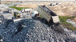 Many Dump Trucks Transfer Mine Stones Fill On a Big Land With Shantui Bulldozer