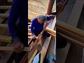 Old carpenter cutting wooden strips on the roof with a manual saw