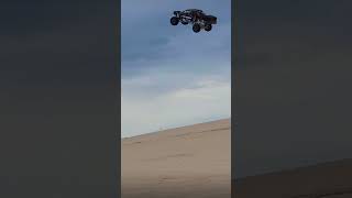 Trophy truck in the dunes goes for huge jump