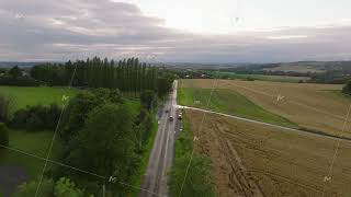 Aerial views capture cars traveling along a scenic countryside road in Belgium. Lush green fields