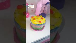 Clarinha fazendo bolo de várias camadas coloridas para as bonecas