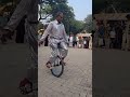 an old man riding one tyre bicycle skillfully.