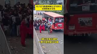 印度一公交车行驶时，男子突然过马路，不料另一辆公交车试图超车，男子遭两辆公交车挤压后摔倒，起身后奇迹般地未受伤。