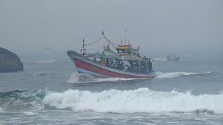 Fishermen come home in the big waves of Puger beach