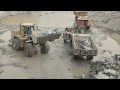 monster wheel loader is roaring caterpillar 966d loading big rocks into big trolleys