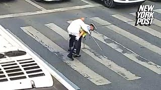 Police officer helps elderly man across the street on his back