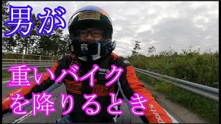 男が重いバイクを降りるとき