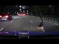 woman sits in middle of road at night with busy traffic