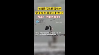 洛阳暴雨致路面积水女子穿拖鞋走在护栏上网友：平衡木高手暴雨过后