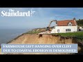 Farmhouse left hanging over cliff due to coastal erosion is demolished