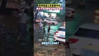 6月26日，山东青岛，暴雨致路上井盖被冲走，两女子合力搬来店里的发财树当警示