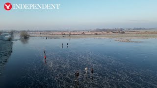 Drone footage shows ice skaters on a frozen flooded field in Cambridgeshire