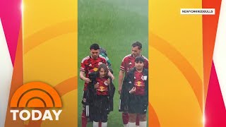 New York Red Bull players give their coats to kids during heavy rain