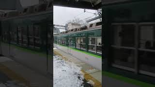 A semi-express train of the Keihan Electric Railway arrives at a station where snow is piling up.