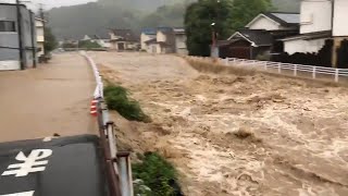 増水して勢いよく流れる川と、冠水した川沿いの道路