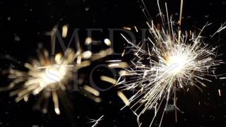 Firework sparkler burning with dancing snowflakes against black night sky background. Winter time