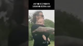 아기를 안고 위험하게 오토바이를 운전하는 남성