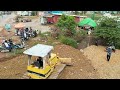 dumping dump truck pouring soil to delete corner operation by komatsu bulldozer working￼￼